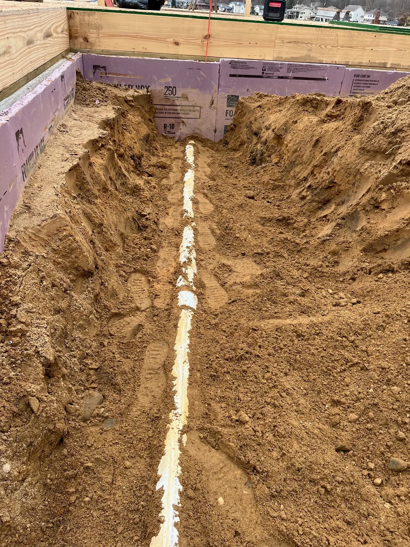 Drain pipe set in a clean open trench alongside a Kalamazoo foundation