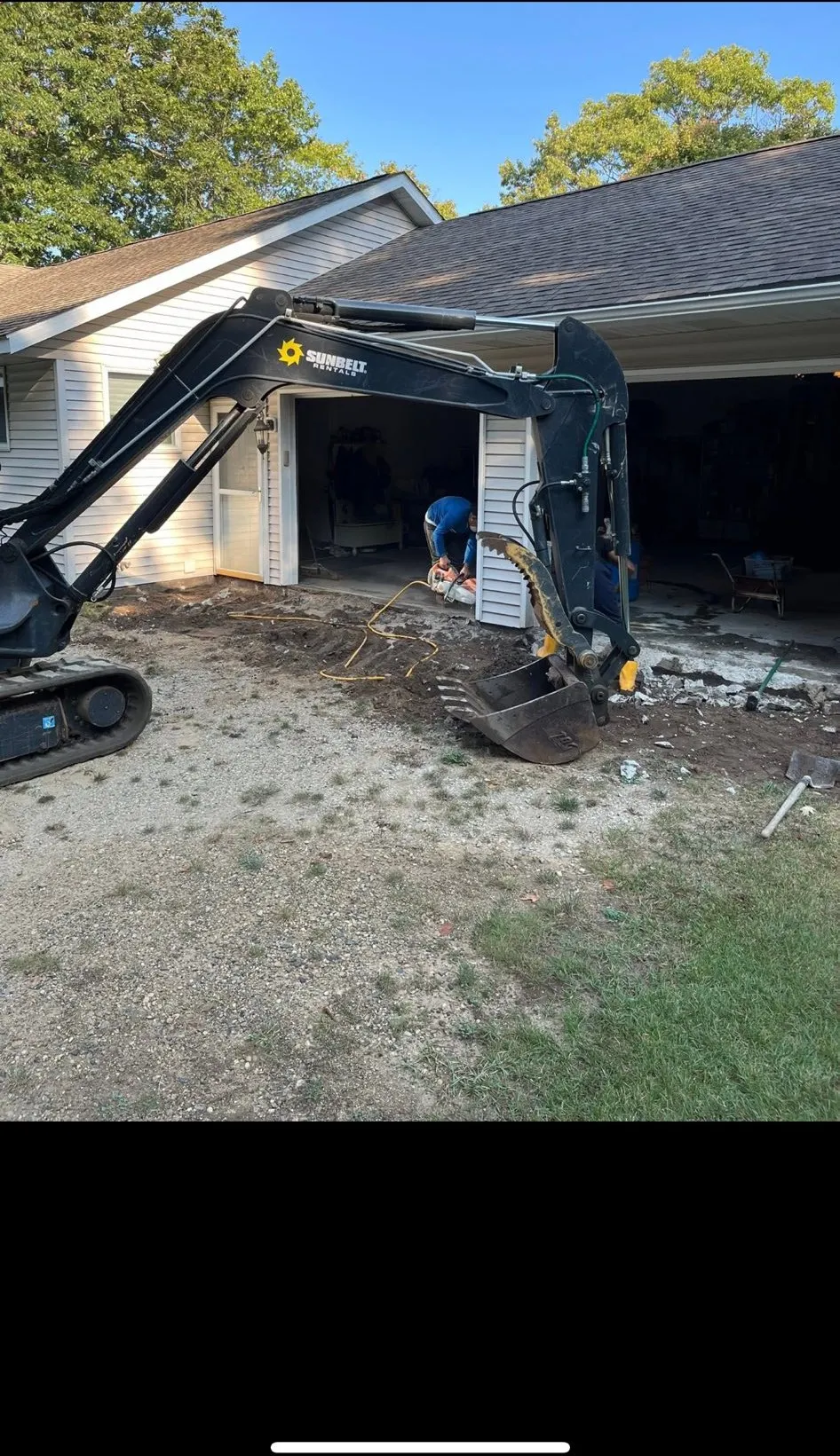 Mini excavator breaking out an old slab at a home garage in Southwest Michigan