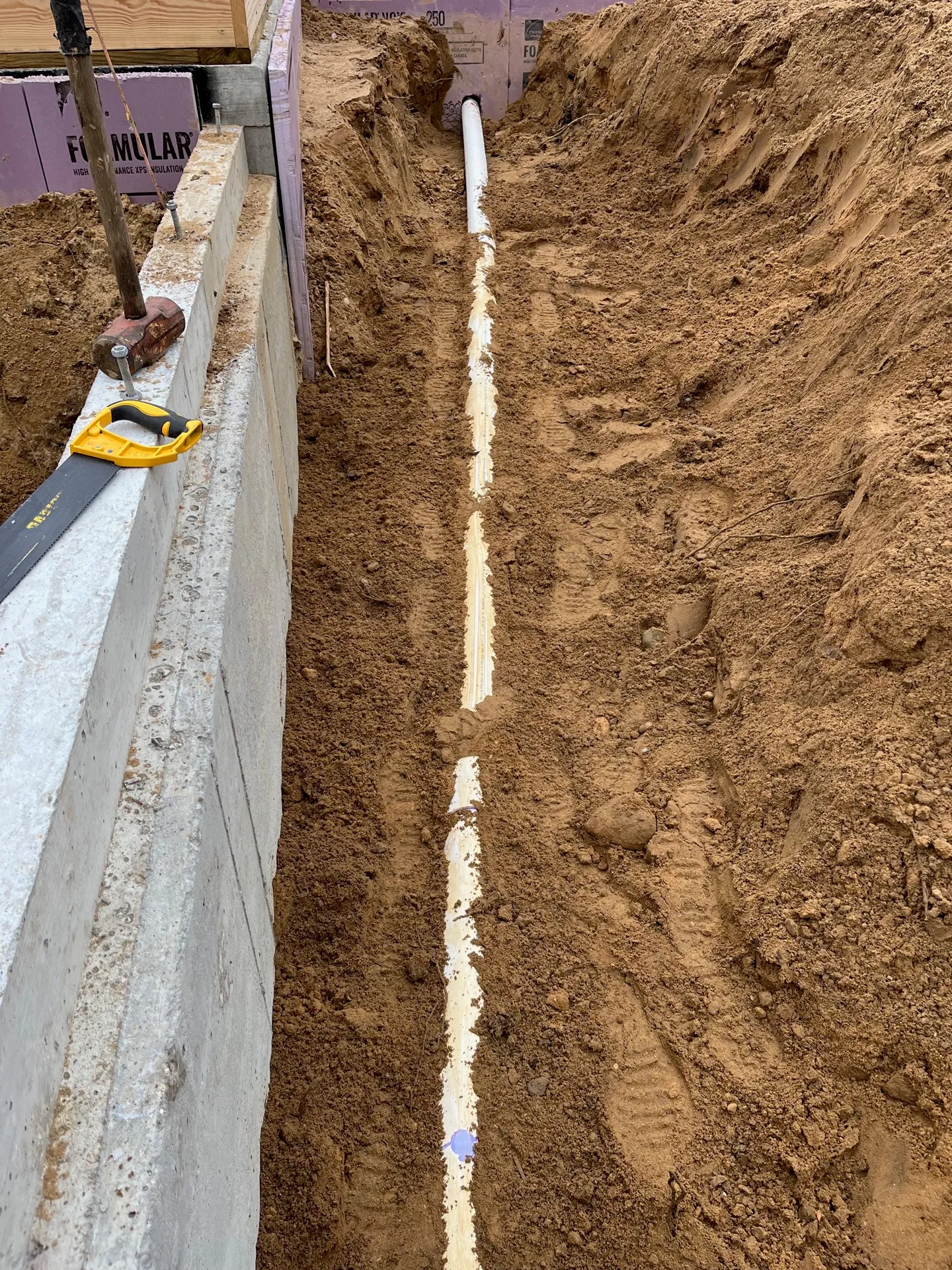 Trench opened alongside a foundation for a new French drain at a Kalamazoo home